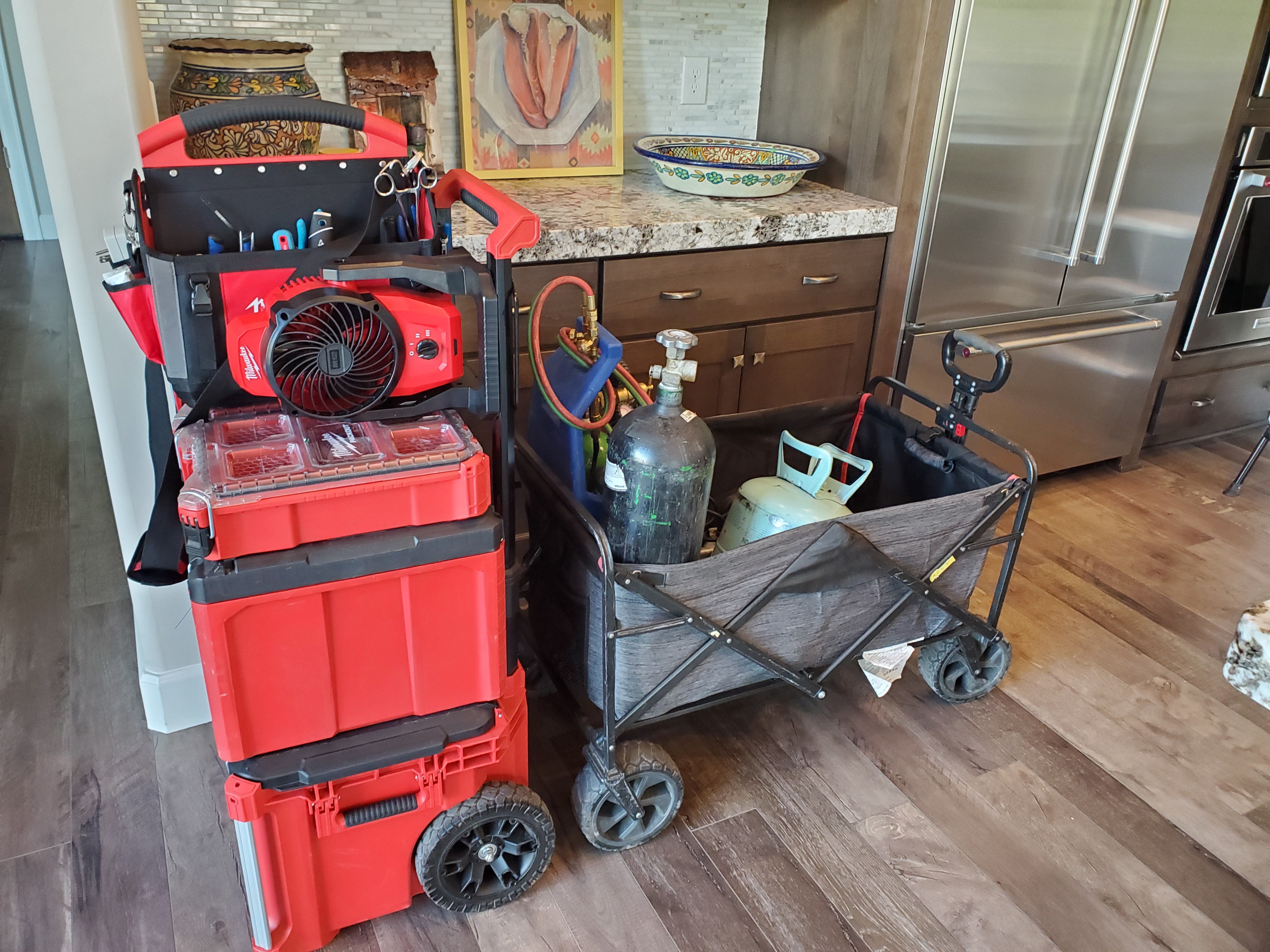 Organized red and black Milwaukee tool storage and refrigeration service equipment in a high-end kitchen